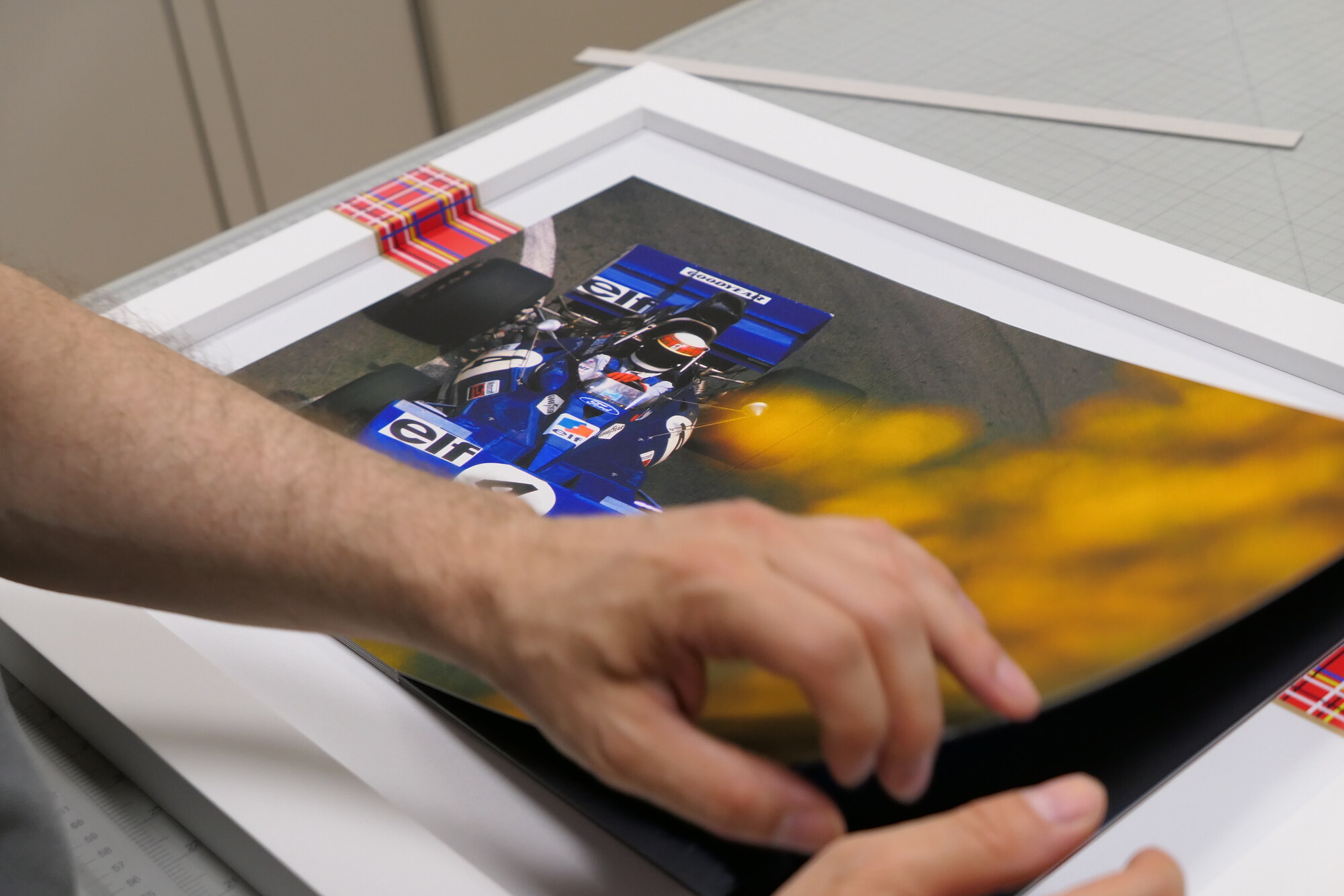 Setting the number 4 spread into the white frame on the cutting table. The tartan band runs across the frame.