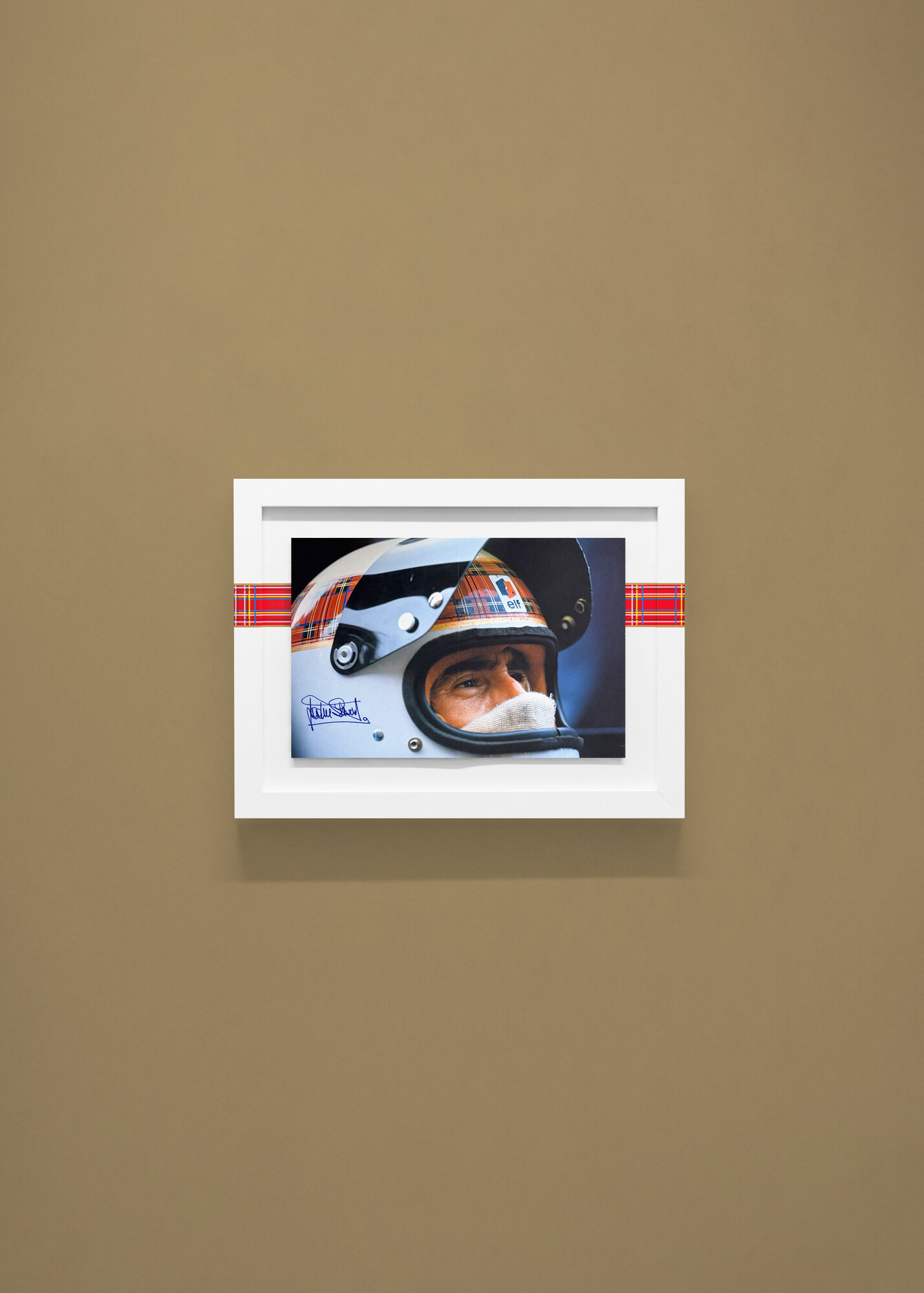 Visualisation, not a photograph. The helmet spread, signed, on an olive wall.